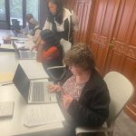 Two Intergenerational Tech Inc. instructors providing hands-on technology support to participants at the University of Louisville HIVE AI Innovation Studio.